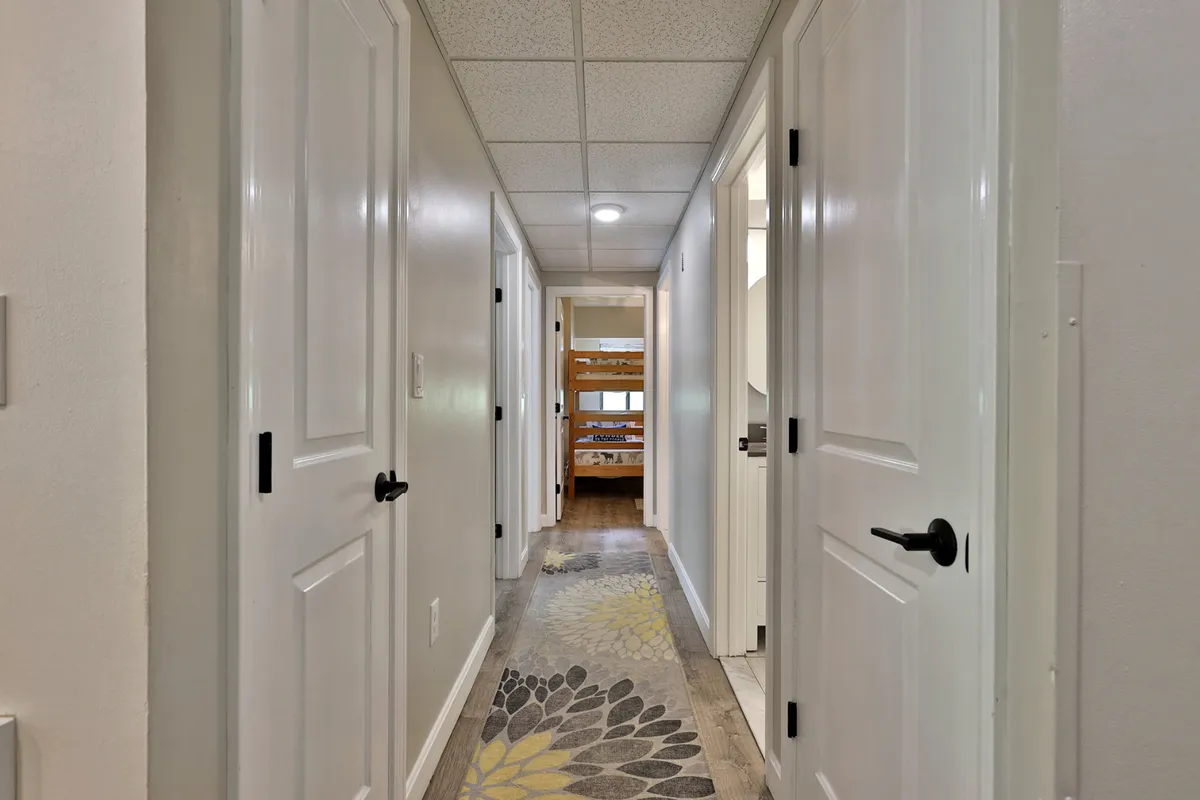 A cozy interior hallway view with bunk beds visible in the distance, a decorative rug, and inviting lighting. The image suggests a warm, family-oriented environment where children can play, enjoy sleepovers, and families can gather after a day of adventure.