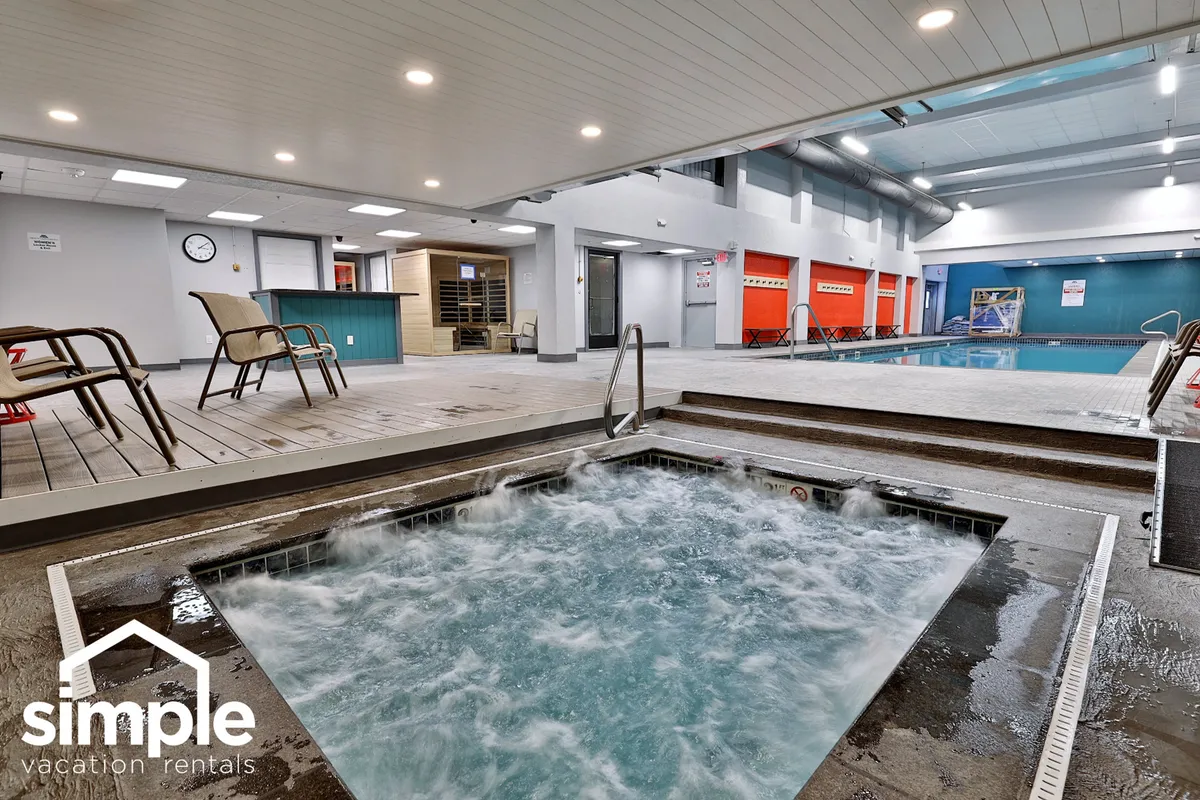 A modern wellness space featuring a hot tub and a swimming pool, bordered by lounge chairs and colorful lockers. The ambiance is calm and rejuvenating, evoking a soothing retreat for post-adventure relaxation.