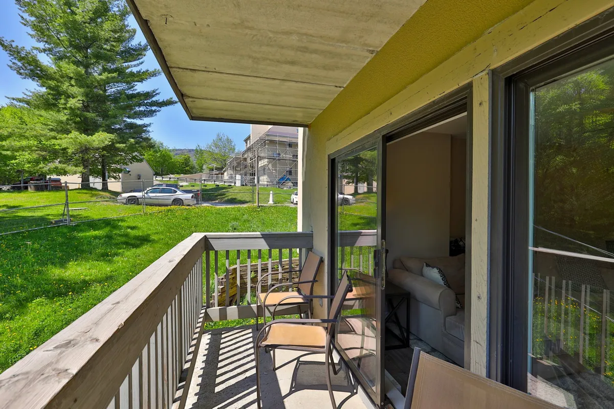 A tranquil private patio with comfortable balcony seating, overlooking a green lawn bordered by distant trees. The space is perfect for enjoying morning coffee or evening relaxation with friends and family, surrounded by natural beauty.