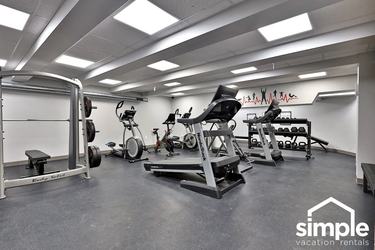 A spacious on-site gym features a variety of weightlifting equipment and cardio machines, complemented by motivational wall art. The setting is bright and energetic, ideal for guests looking to start their wellness routines or get energized for the day.