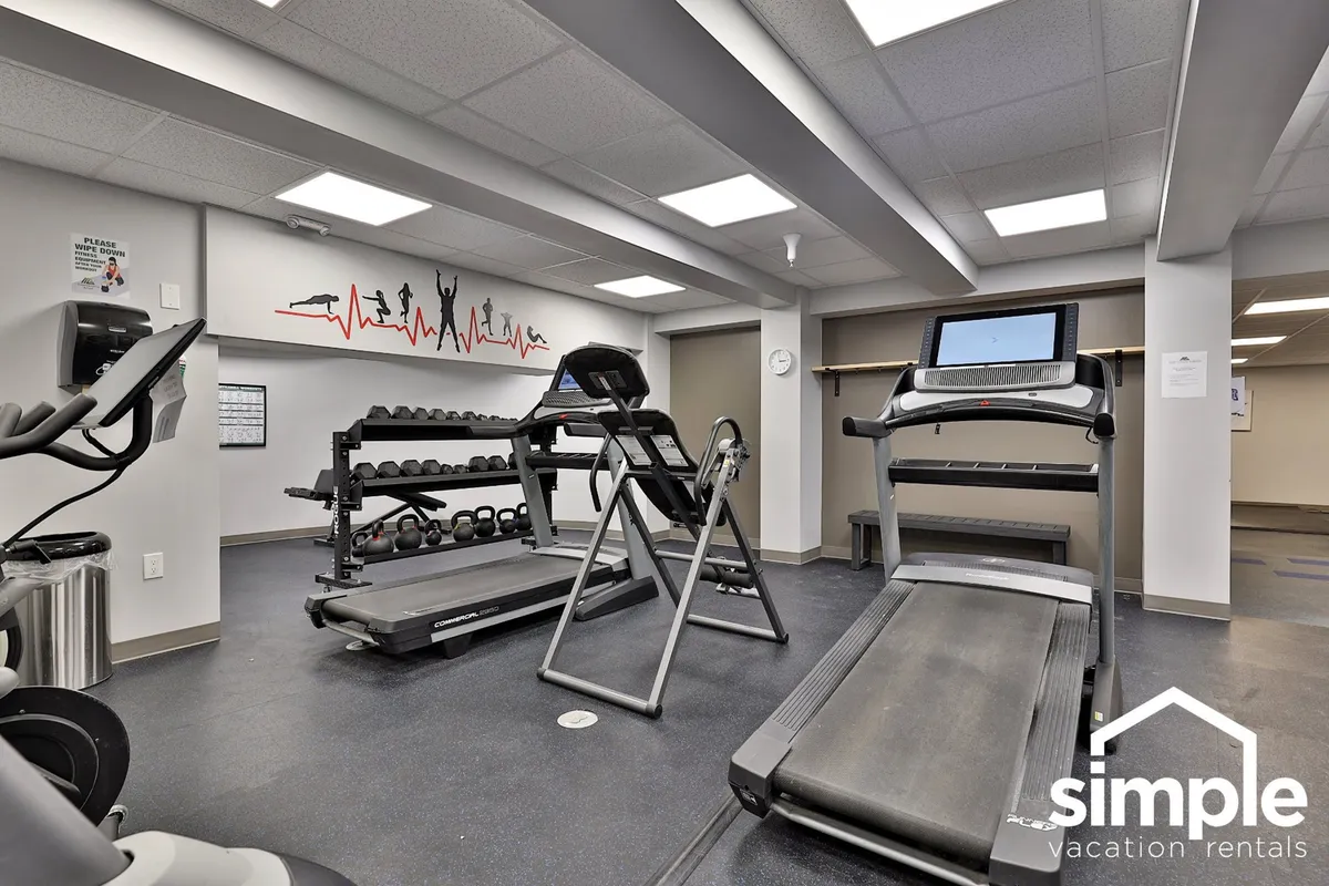 A motivating gym area equipped with treadmills, a dumbbell rack, an exercise bike, and motivational wall art. The lively, communal atmosphere captures the essence of shared fitness spaces and opportunities to engage with fellow residents.